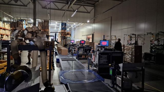 IT technikos nuoma filmavimui — sandėlio aikštelė su scenarijaus ekranais palei konvejerio liniją